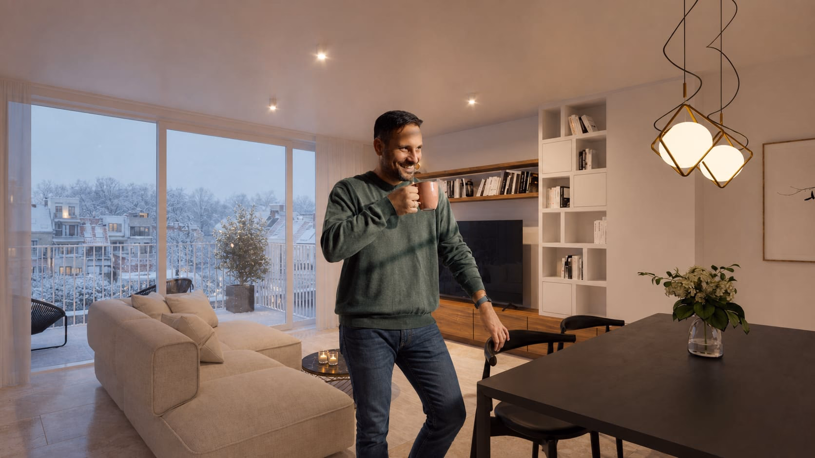 Man met een koffiekop in een warme leefruimte, met besneeuwde daken achter het raam